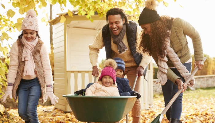 Parents In Fall Giving Children A Ride In Wheelbarrow